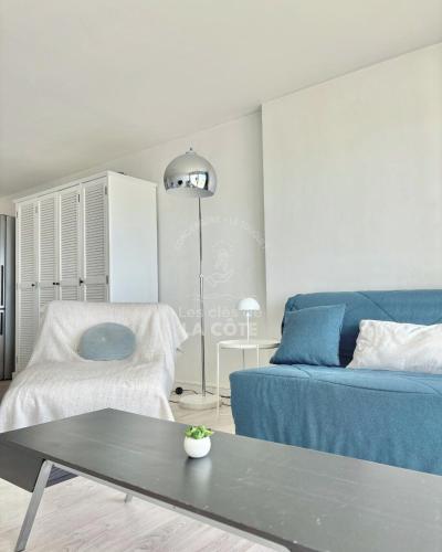 un salon avec un canapé bleu et une table dans l'établissement Côté Mer, à Le Touquet-Paris-Plage