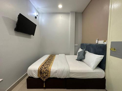 a bedroom with a bed with a television on the wall at SS Grey Hotel kl in Kuala Lumpur