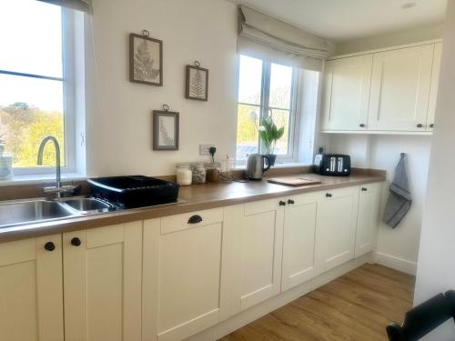 a kitchen with white cabinets and a sink and a window at Five bedroom family house in St. Leonards