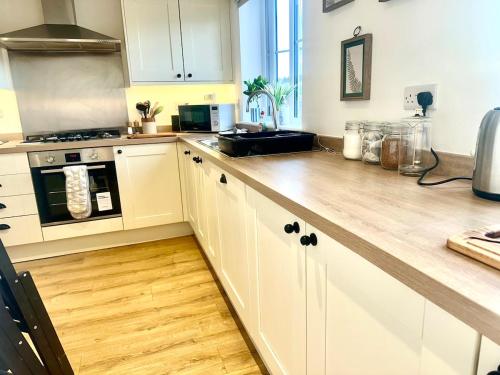 a kitchen with white cabinets and a wooden counter top at Five bedroom family house in St. Leonards