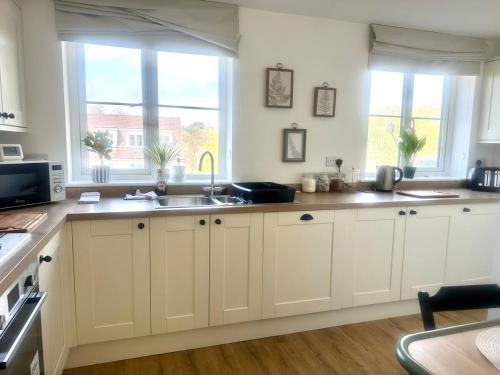 a kitchen with white cabinets and a sink and windows at Five bedroom family house in St. Leonards