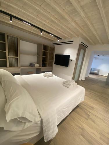 a bedroom with a white bed and a television at Fabrikas in Mýkonos City