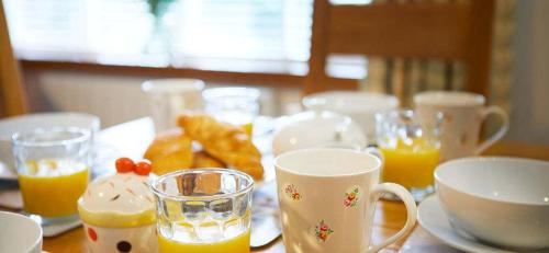 a table topped with cups of orange juice and bread at Beach Approach Cottage - 30 steps from beach - Luxury house with covered table tennis - Netflix Smart TV in Filey