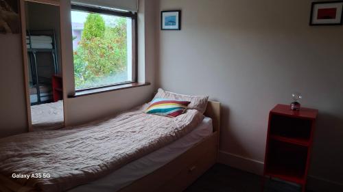 a small bedroom with a bed and a window at Artisthostel Letterkenny in Letterkenny