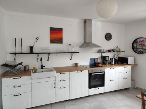 a kitchen with white cabinets and a wooden counter top at Casa Barroca in Figueiró dos Vinhos