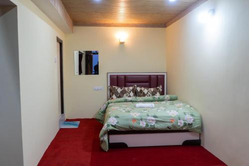 a bedroom with a bed with a red carpet at Gangamaya Homestay in Darjeeling