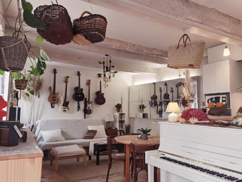 un salon avec un piano et un salon avec des guitares sur le mur dans l'établissement Chez Camille & Olivier, chambres, à Esparron-de-Verdon