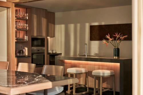 a kitchen with a bar with chairs and a table at Regent Phu Quoc in Phu Quoc