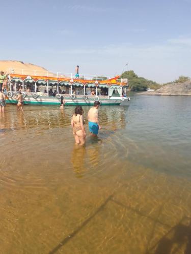 two people standing in the water in front of a boat at Nubian Life Nile View in Aswan