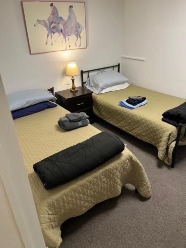 a room with two beds and a table with a lamp at Art Gallery Hostel in Whitefield