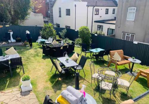 a backyard with tables and chairs and a fence at The Cobham Hotel in Southend-on-Sea