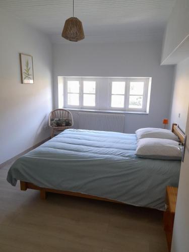 a bedroom with a large bed and two windows at La Minoterie du Lot in Estaing