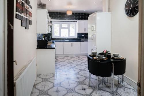 a kitchen with a black table and white cabinets at Spacious 6 bedroom House in Dudley with optional Nursery-Drive and Garage-Families and Contractors Welcome in Tipton
