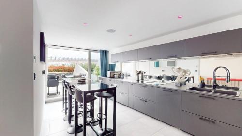 une cuisine avec des armoires grises et une table et des chaises dans l'établissement Le Majestic, Naturist Village 3 bedrooms 90 m2, au Cap d'Agde