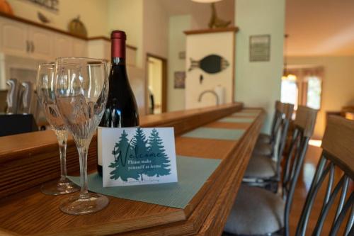 a bottle of wine and two wine glasses on a table at Hideaway Riverfront Cabin in Kernville with Universal EV Charger in Kernville