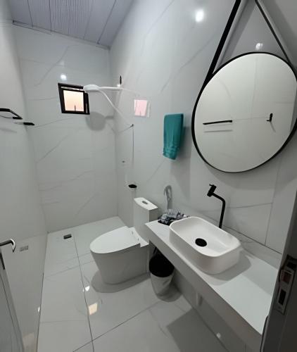a white bathroom with a sink and a mirror at AP 6 C/Garagem>Ar>Wifi>Cozinha>Tv Disney+>Pet free in Ji-Paraná
