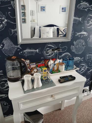a white dressing table with a mirror on a wall at Marjune Guest House in Weymouth