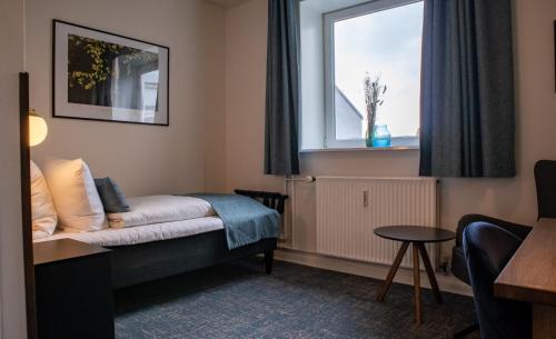 a hotel room with a bed and a window at Hotel Phønix Hjørring in Hjørring