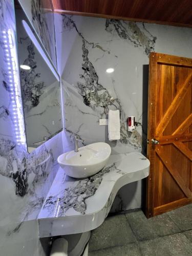 a bathroom with a sink and a marble wall at Arenal Rústic Lodge in Fortuna