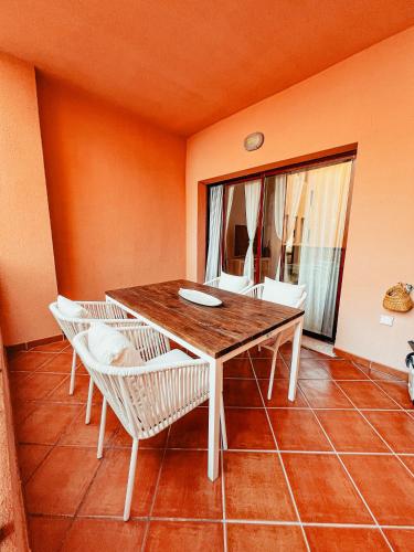 a dining room with a wooden table and white chairs at CN-340 Suites in Estepona