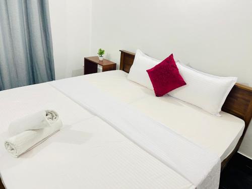 a bed with white and red pillows on it at Dreamy Heaven Negombo in Negombo