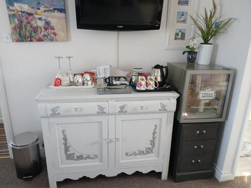 a white cabinet with a sink and a tv on top at Marjune Guest House in Weymouth