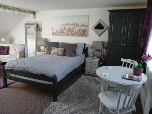 a bedroom with a bed and a table and a chair at Marjune Guest House in Weymouth