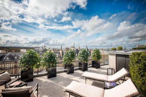 a rooftop patio with chairs and potted plants at Mandarin Oriental Lutetia, Paris in Paris