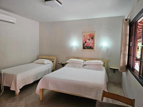a bedroom with two beds and a window at Pousada do Alferes in Paty do Alferes