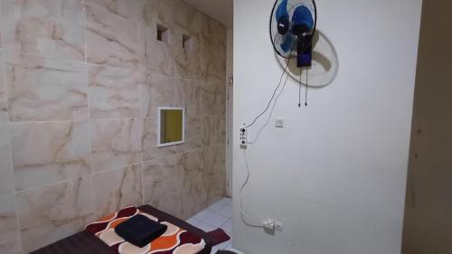 a bathroom with a stone wall and a fan at Kost Carmelia Syariah Baranangsiang Bogor in Bogor