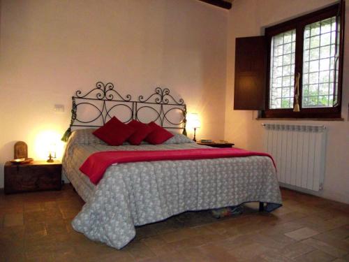 a bedroom with a large bed with red pillows at Casale La Quercia in Pian D'artino
