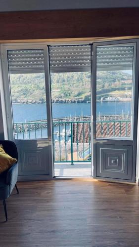a room with two large sliding doors with a view of the water at Casa da Marina de Angra in Angra do Heroísmo