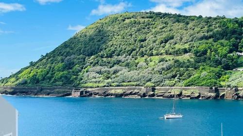 ein Boot im Wasser neben einem Berg in der Unterkunft Casa da Marina de Angra in Angra do Heroísmo