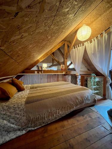 un lit dans une chambre avec un plafond en bois dans l'établissement la cabane savoyarde, à Truison