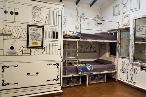 a room with bunk beds and a wall with drawings on it at Pappi Chulo Vagator in Vagator