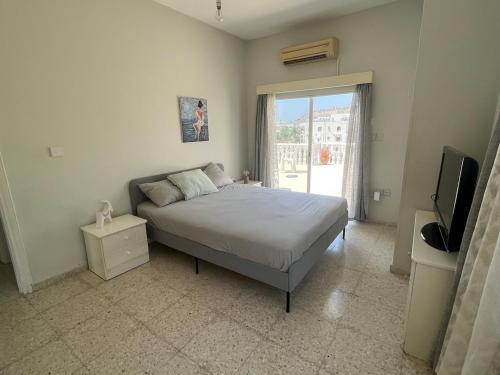 a bedroom with a bed and a tv and a window at Huge Terrace in peaceful Oroklini in Voroklini
