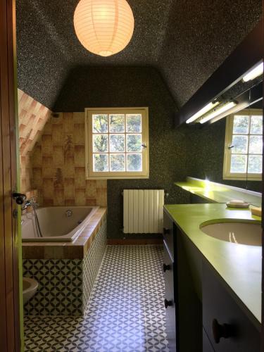 une grande salle de bain avec une baignoire et un lavabo dans l'établissement Morlaix - Maison au milieu des bois, à Plourin