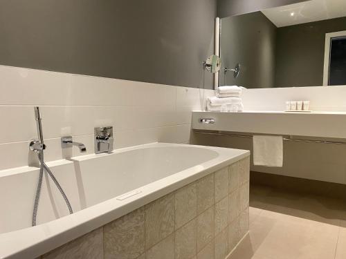 a bathroom with a large tub and a mirror at Van der Valk Hotel Brussels Airport in Diegem