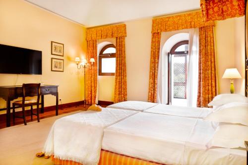 a bedroom with a large white bed and a desk at Pousada Convento de Vila Viçosa in Vila Viçosa