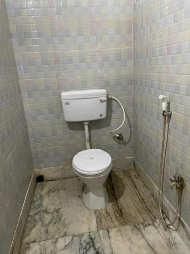 a bathroom with a toilet in a tiled room at Hotel Maa Durga Guest House Near Beach in Digha