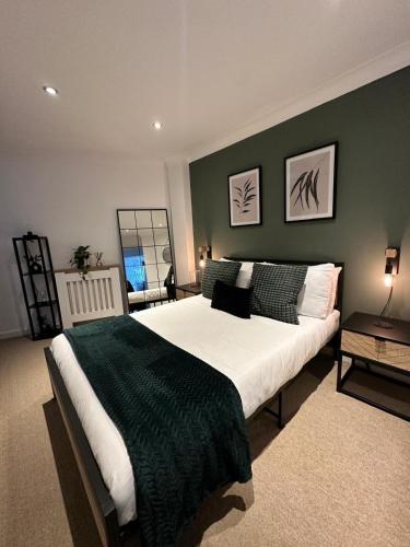 a bedroom with a large bed with a green wall at The Central Nook - Contactors and Holidaymakers in Cardiff