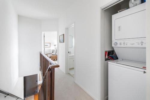 a white kitchen with a refrigerator and a staircase at 7 Pelican! Sweeping Ocean Views & Front Row Beach Access in Watsonville