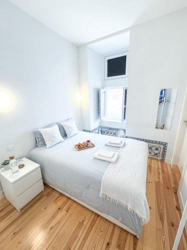 a bedroom with a white bed and a wooden floor at Room in the Heart of Historic Lisbon on Rua Augusta in Lisbon