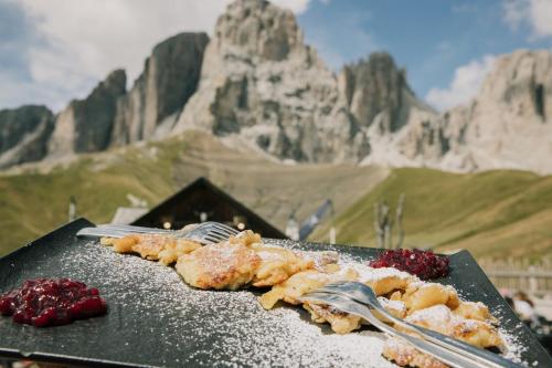 un piatto di cibo con due forchette e una montagna di Appartamenti Césa Col De Pin a Canazei