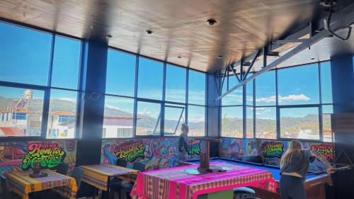 a room with a table and chairs and windows at Magic Packer Hostel in Cusco