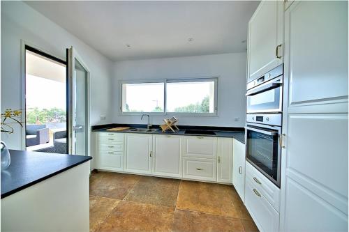 une cuisine blanche avec un évier et une cuisinière dans l'établissement Casa Angelina - Villa piscine chauffée vue mer, à Ajaccio