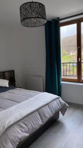 une chambre avec un lit et une grande fenêtre dans l'établissement La Risloise, à Pont-Audemer