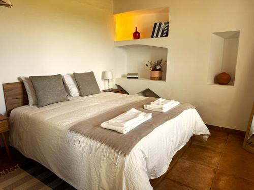 a bedroom with a large bed with towels on it at Refúgio sobre a paisagem alentejana in Mora