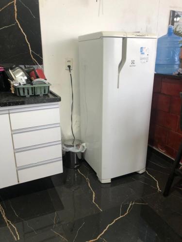 a white refrigerator in a kitchen next to a counter at Casa com piscina em Iranduba in Iranduba