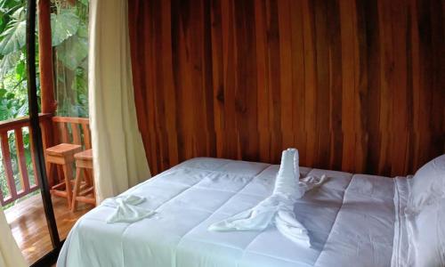 a bedroom with a white bed with a wooden wall at Arenal Rústic Lodge in Fortuna